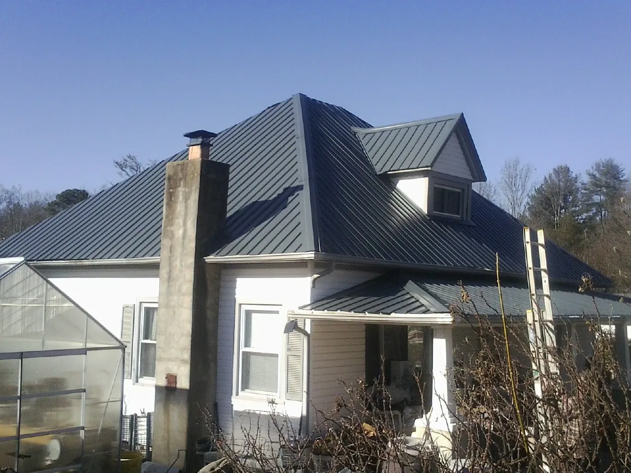 Dark blue standing seam metal roof on a white farmhouse with dormer — Slate & Tile Roof Repair by Roofing Brothers in Bourbonnais