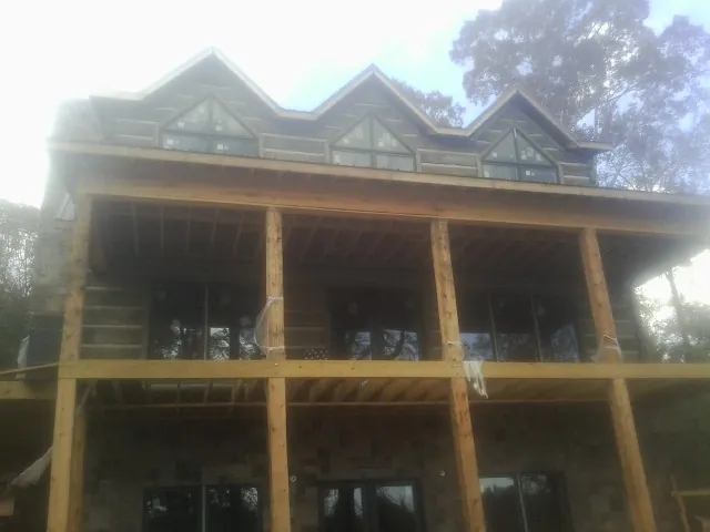 Dormers and porch framing on a large log home under construction — Roof Coating work by our crew in Bourbonnais