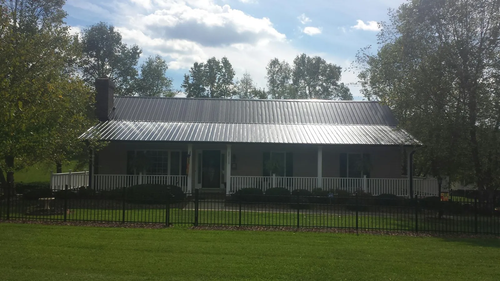 Gray metal roof on a brick ranch with a full width front porch — Gutter Guard Installation work by our crew in Bourbonnais