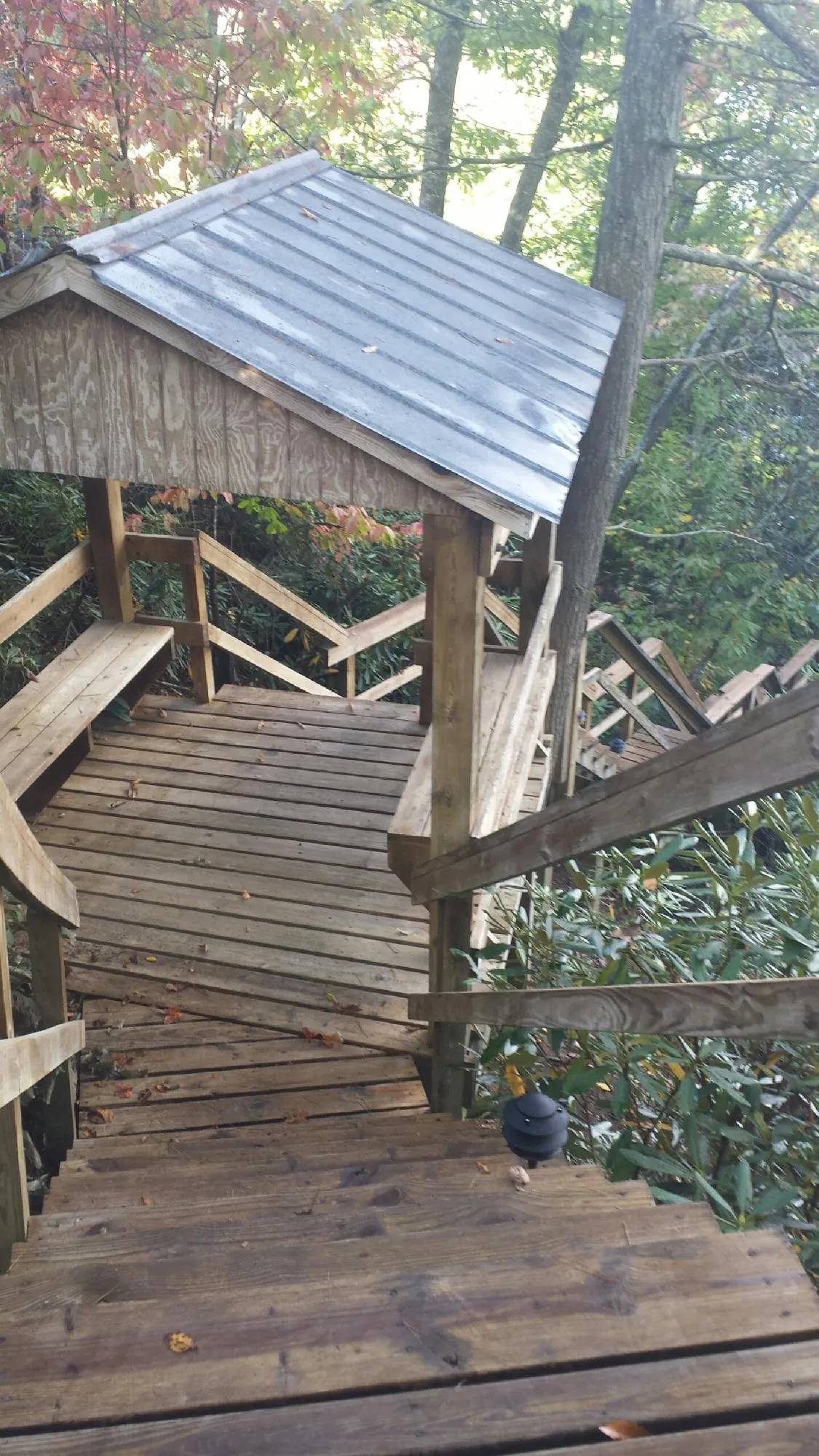 Metal roofed shelter over wooden steps on a wooded walkway — Skylight Repair & Installation work by our crew in Bourbonnais