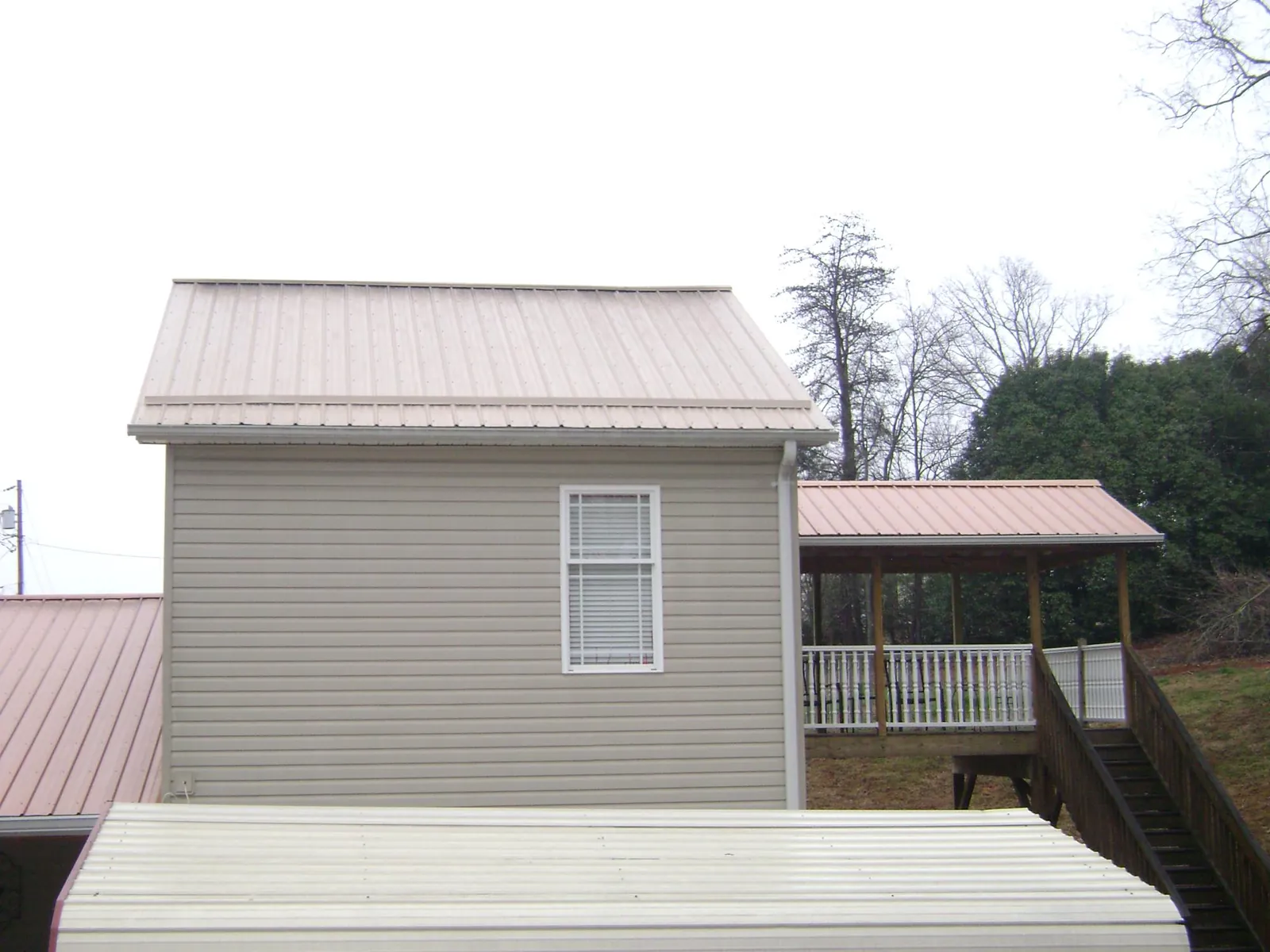 Tan metal roofs on a two story addition and attached porch, from a Roof Replacement job in Bourbonnais