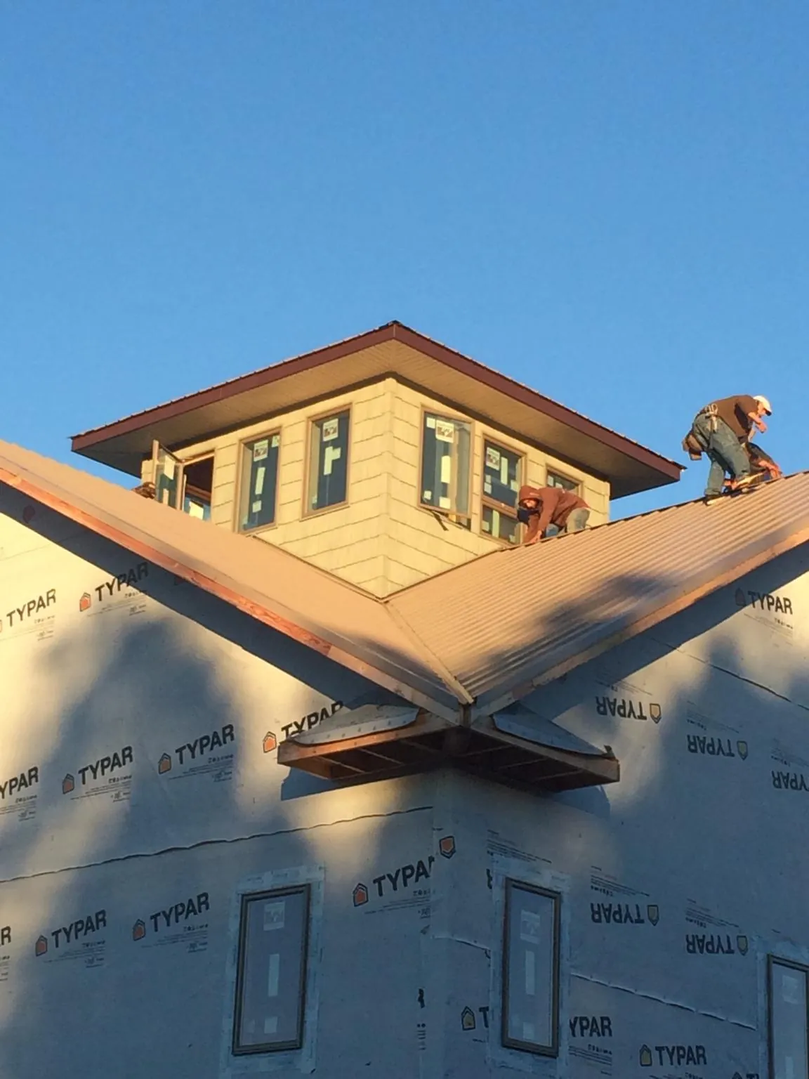 Roofers working around a rooftop cupola on a new metal roof at sunset — Roof Waterproofing in Bourbonnais by Roofing Brothers